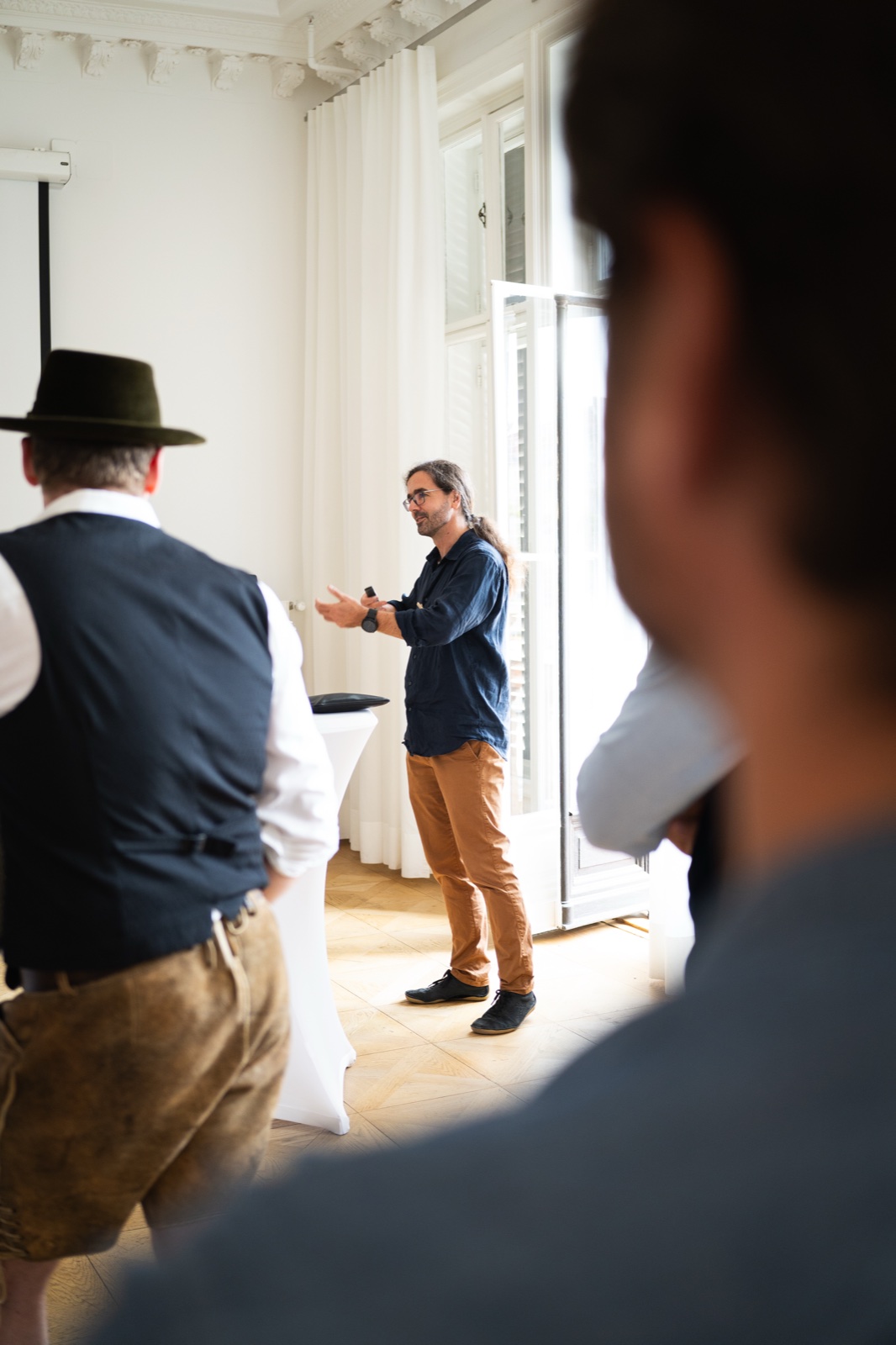 Stefan Christoph speaking to a standing audience in a bright room at the Xingu Media Wiesn pre-event